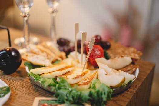 Plateau de fromages et fruits frais avec des piques, accompagné de crackers et de raisins sur une table en bois.